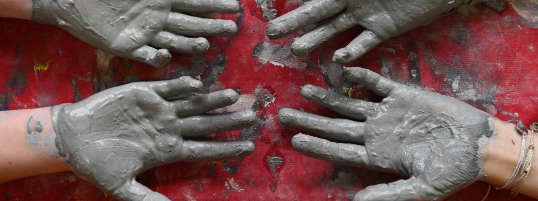 student hands covered in clay